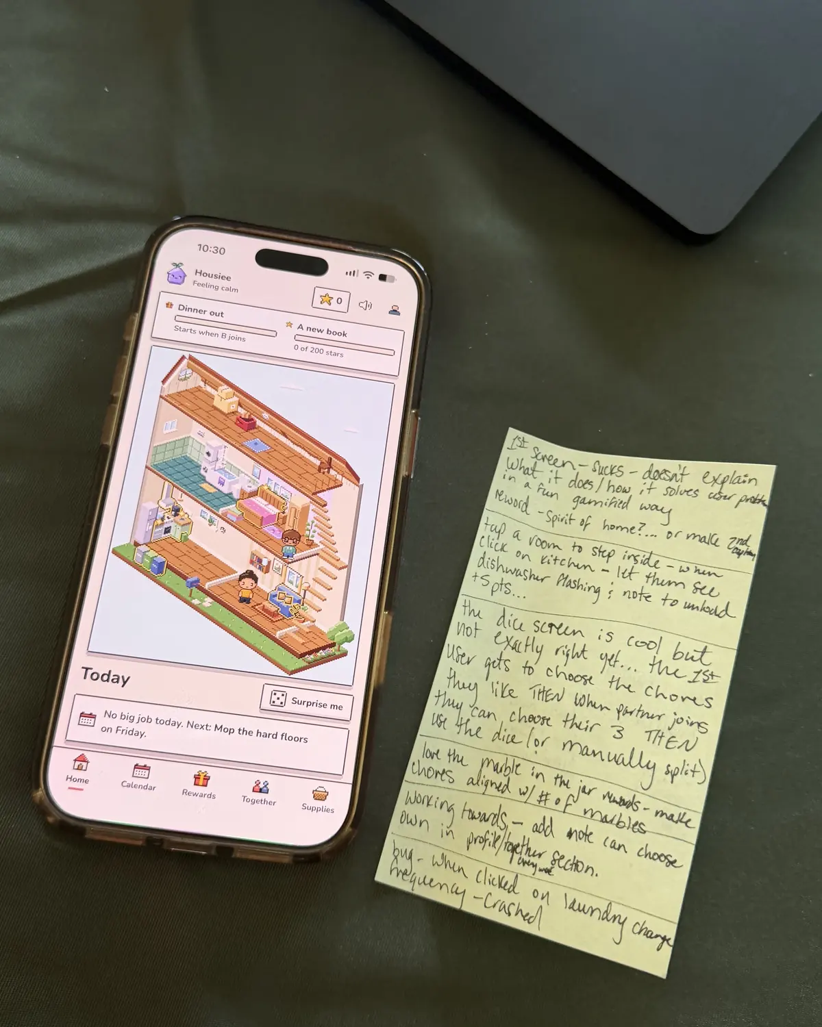 An early build of the app on an iPhone, still named Housiee, next to a handwritten sticky note of test feedback