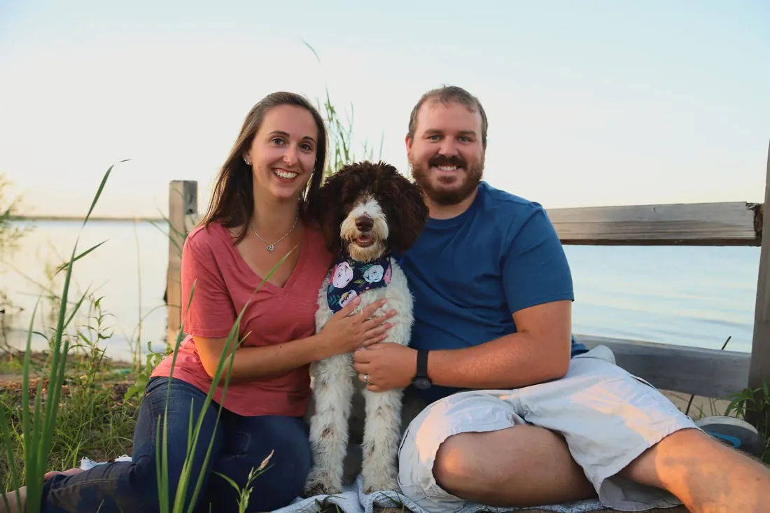 A couple and their doodle on the shore