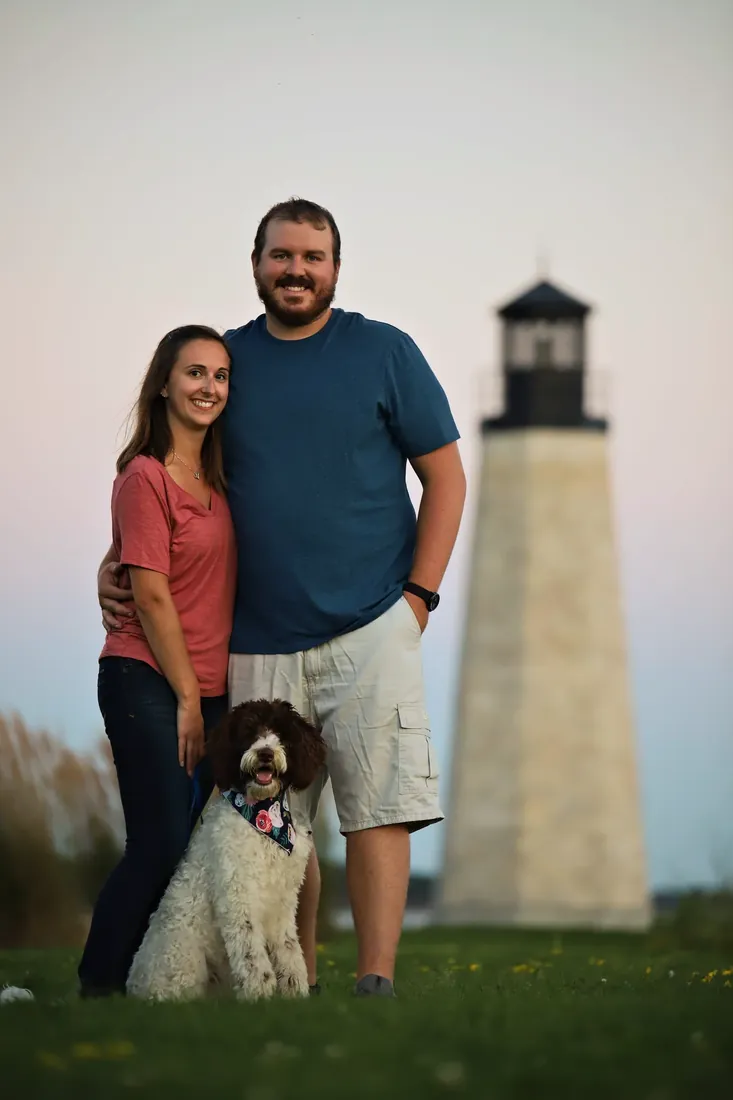 Under the lighthouse, the dog at their feet