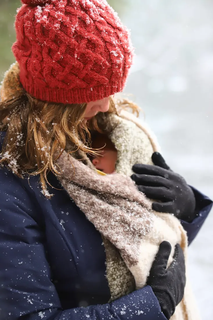 A brand-new baby tucked into a scarf in the snow