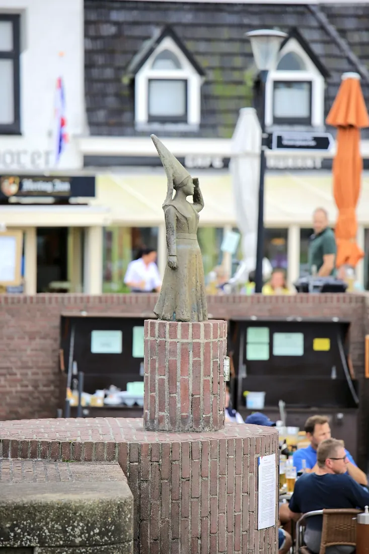 A statue watching over the harbour cafes