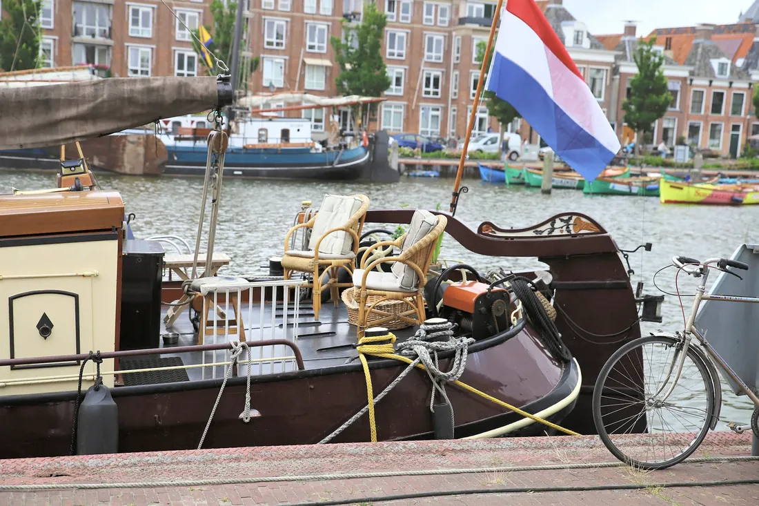 A boat dressed up with wicker chairs and a flag