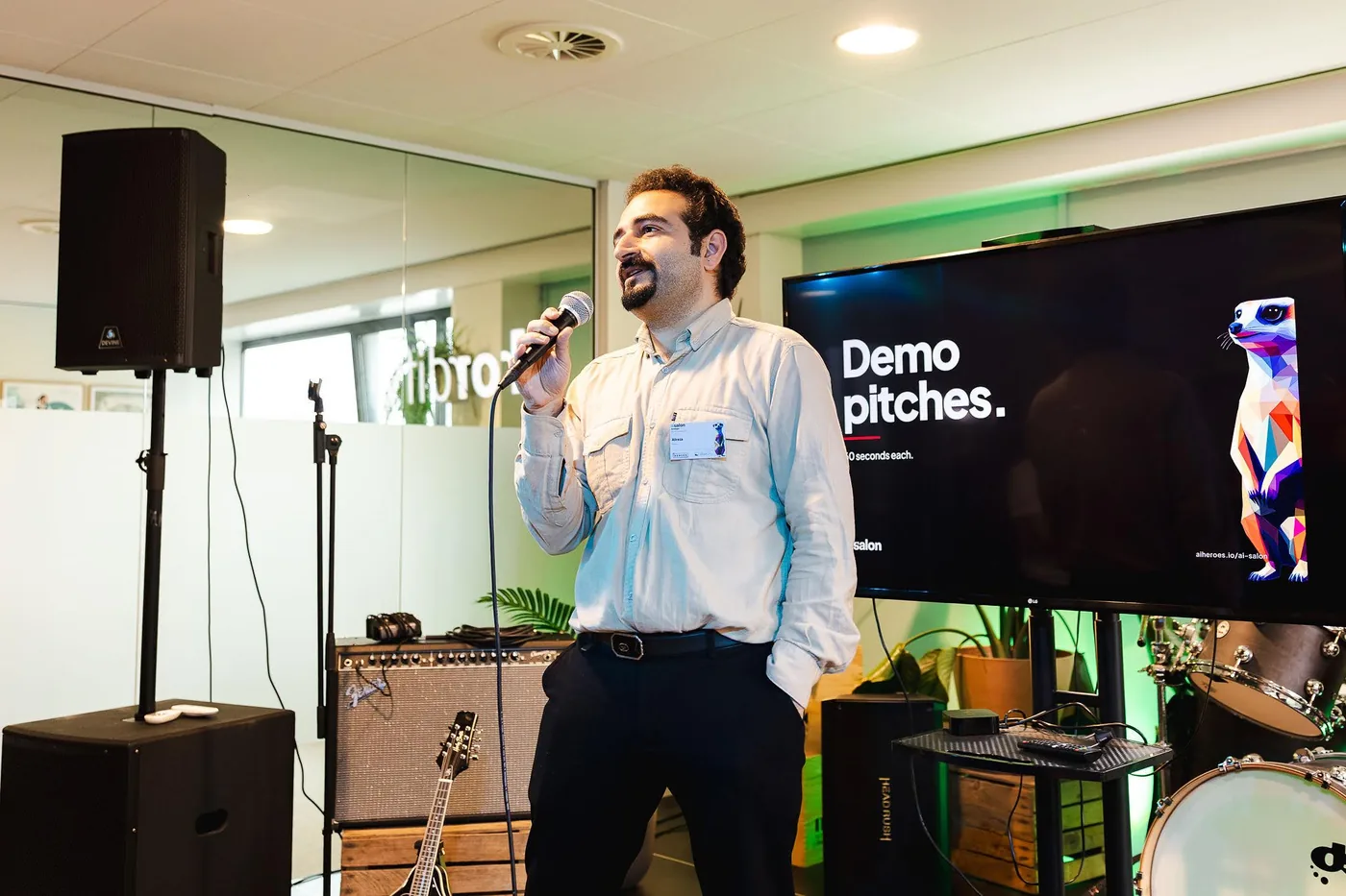 A founder with a microphone in front of a screen that says Demo pitches