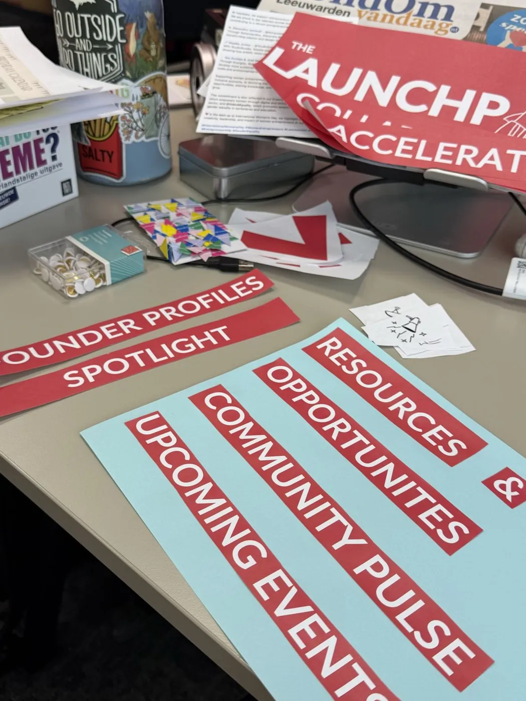 Printed headers for the Launchpad on a desk: founder profiles, opportunities, community pulse and upcoming events