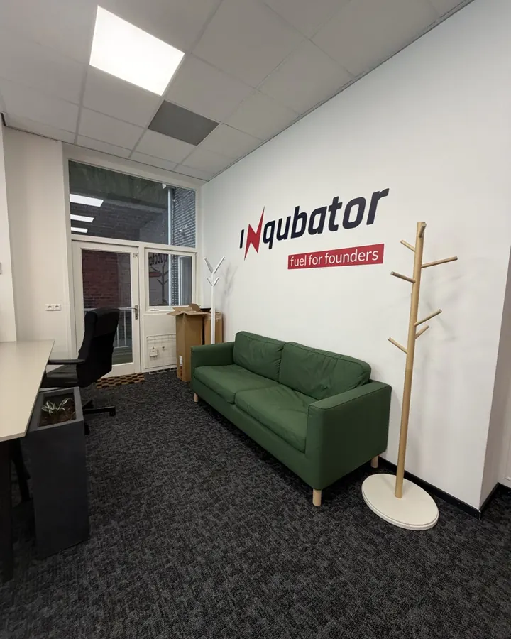 The room in February 2026, with a green sofa under the Inqubator logo