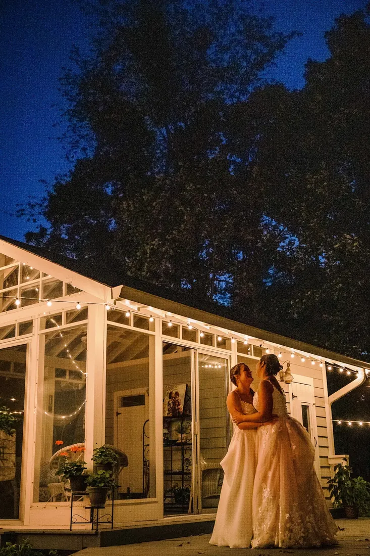 Cece & Erica: in front of the lit-up garden room at night
