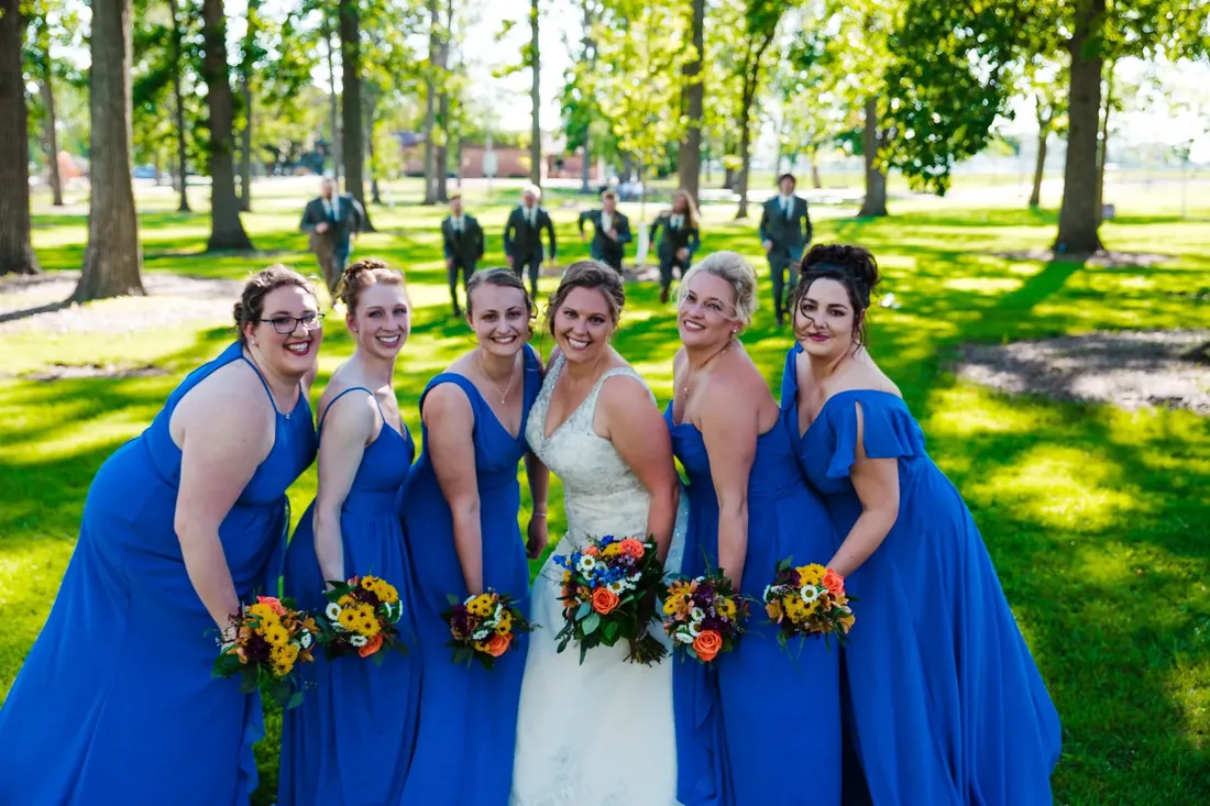 Trisha & Mark: bridesmaids in blue, the groomsmen running up behind