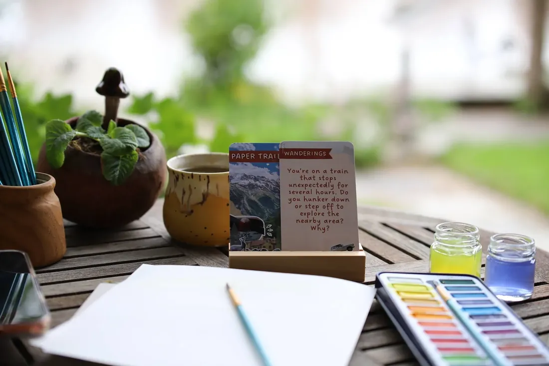 A question card on its stand, next to the watercolours