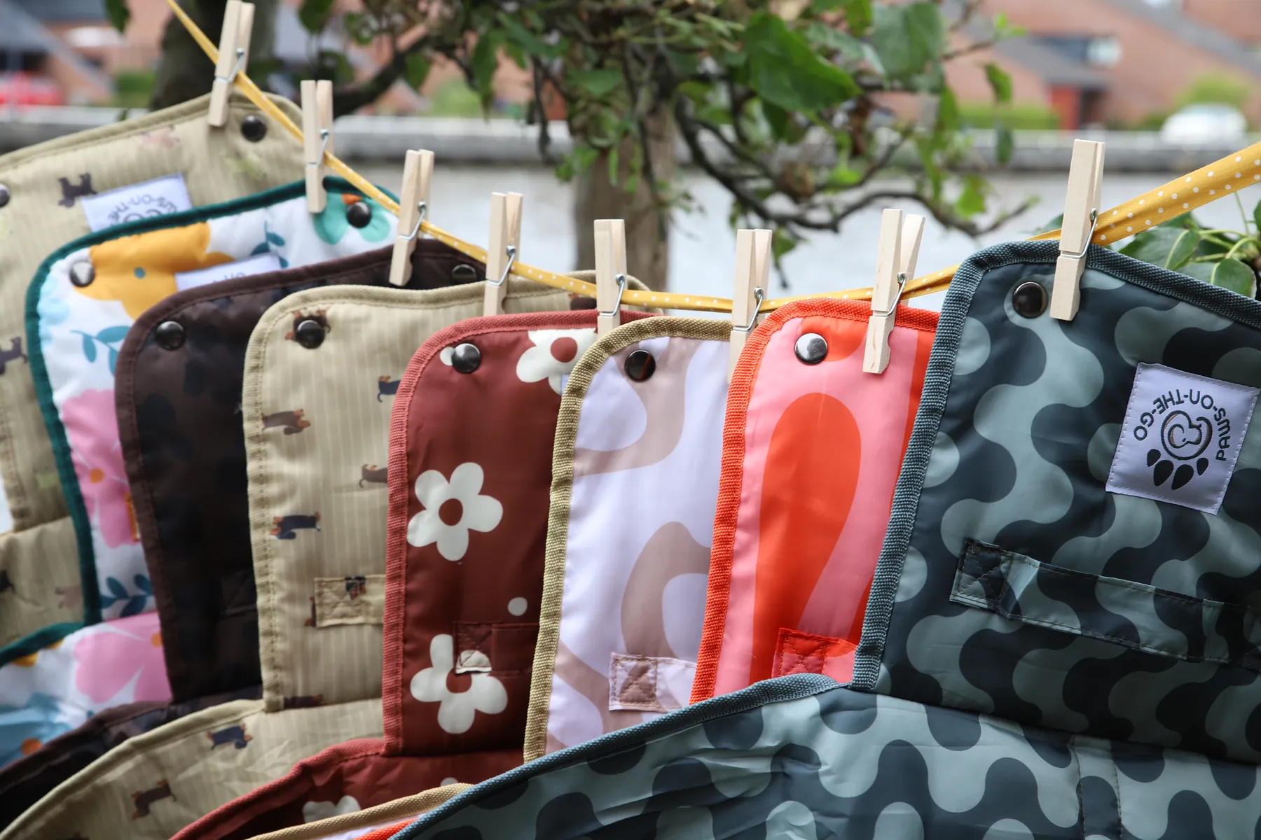 PawsOnTheGo mats on a clothesline, carried by the handle, stacked, and under a dachshund on the grass