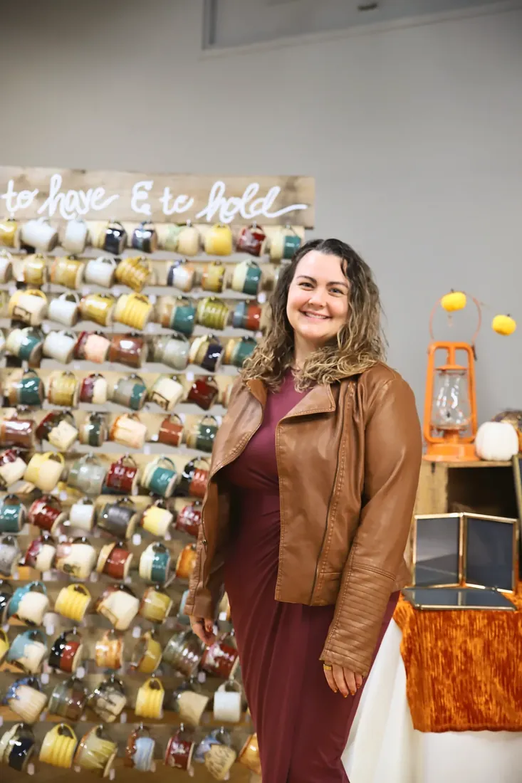 Abby in front of her mug wall