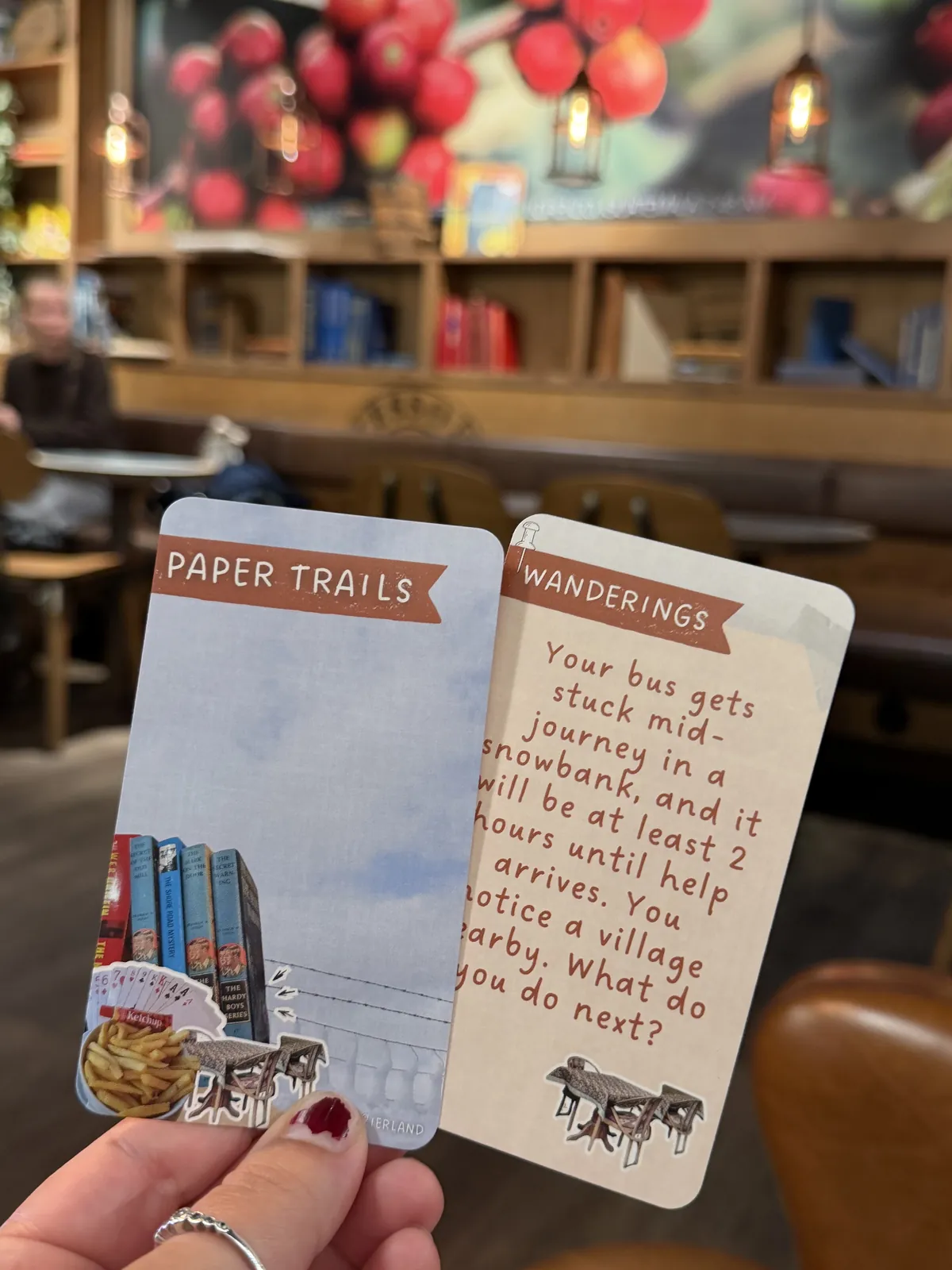 A hand holds up a card front and its English question, about a bus stuck in a snowbank, in a cafe