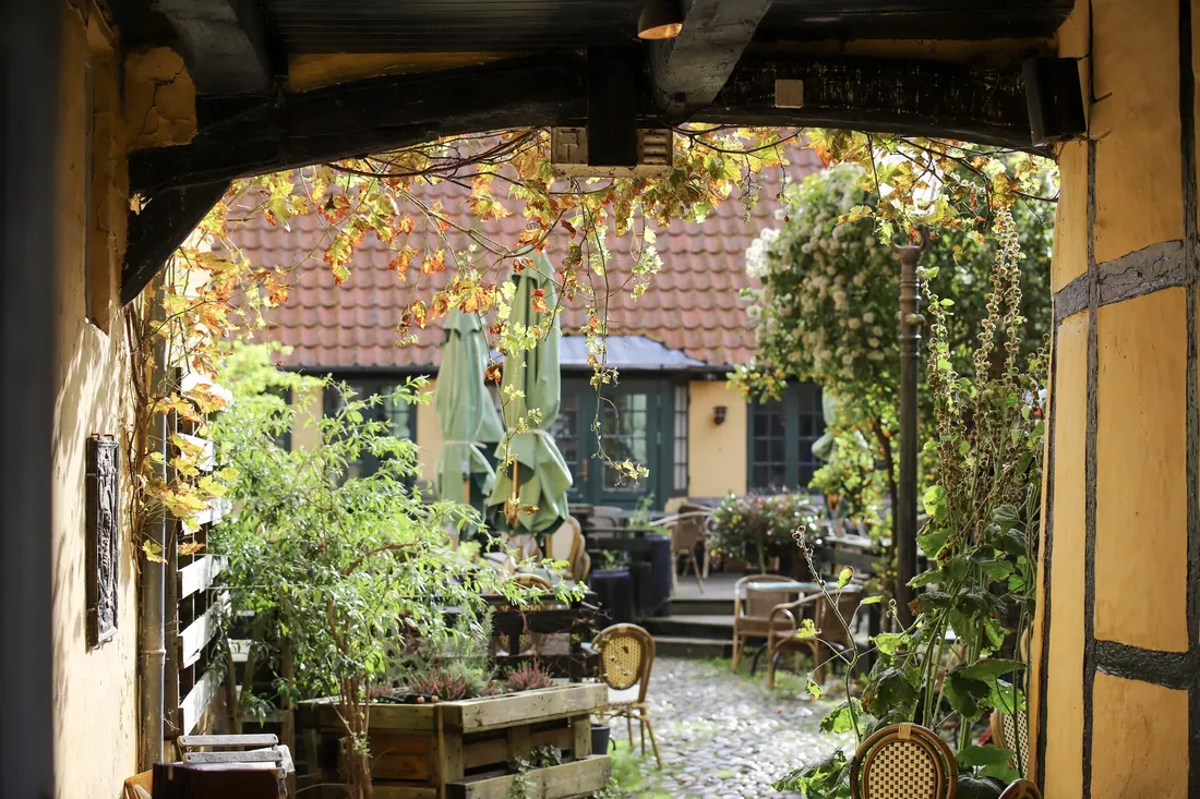 A courtyard cafe seen through an old gateway