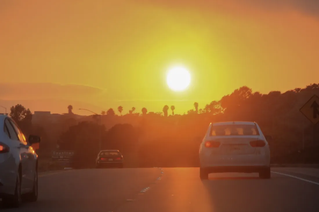 A car driving into a low orange sun