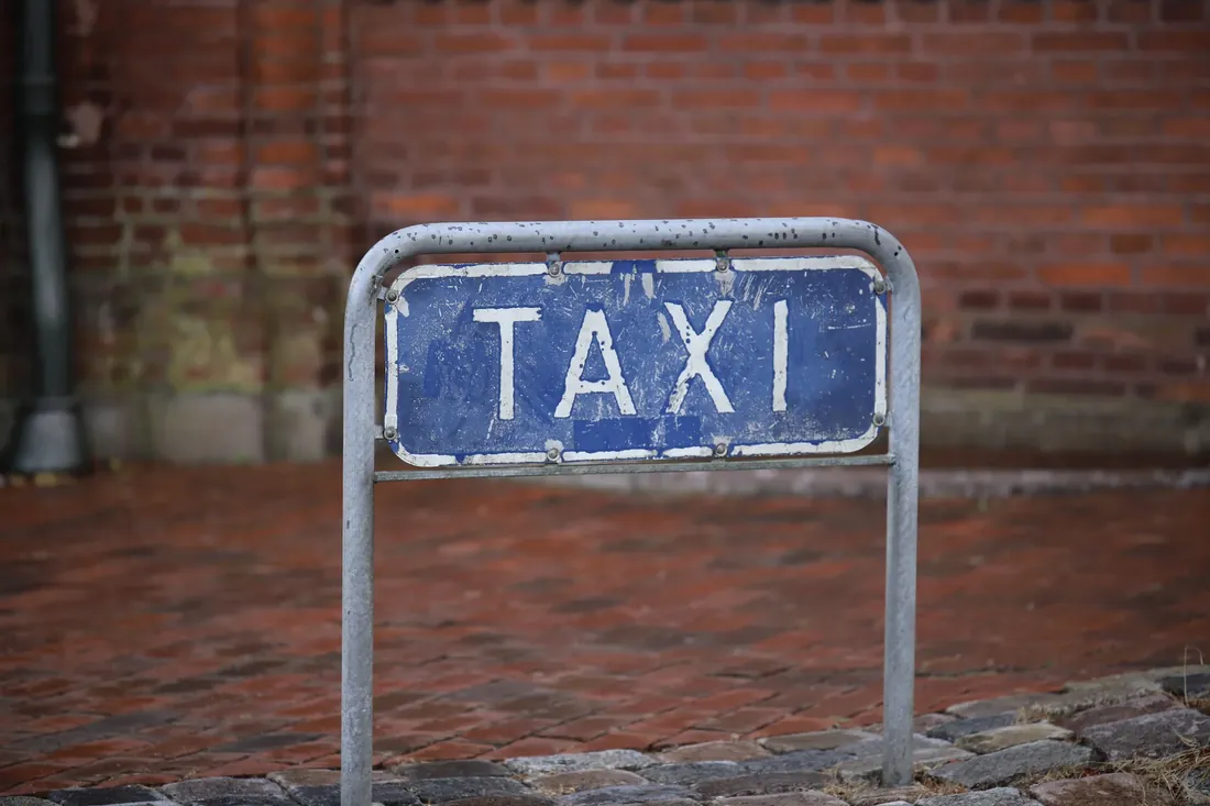 A blue taxi sign on red brick