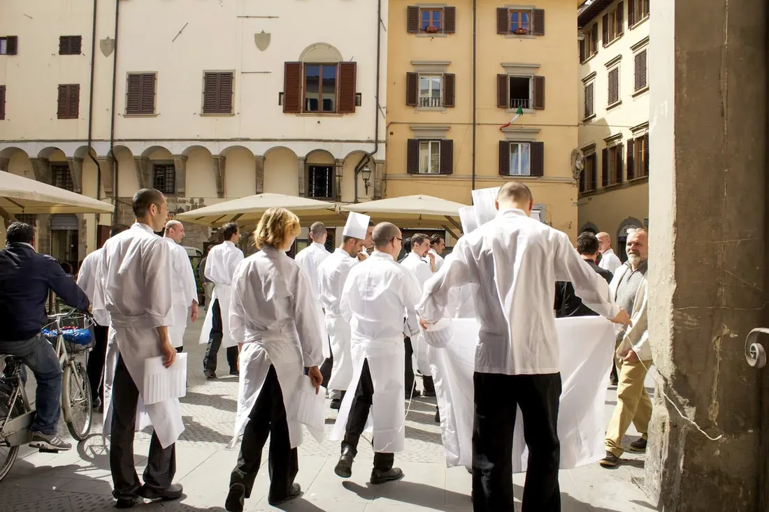 Waiters in white aprons crossing a piazza, Italy