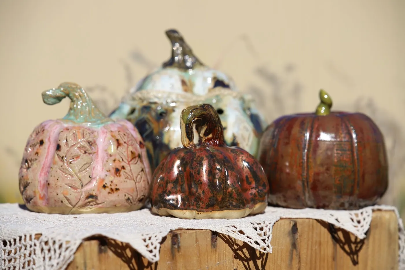 4 ceramic pumpkins in mixed glazes on the same lace